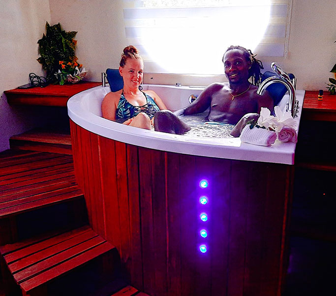 Couple se détendant dans un jacuzzi avec chromothérapie au Natiora Green Lodge.