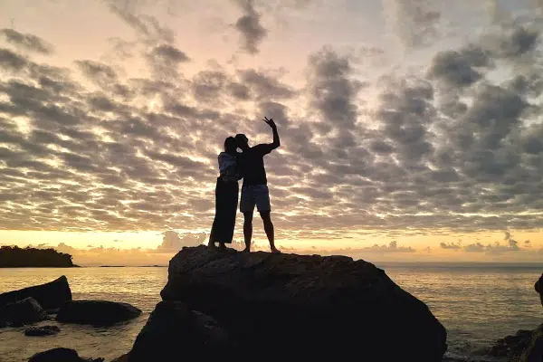 Silhouette de couple en lune de miel admirant un coucher de soleil spectaculaire.