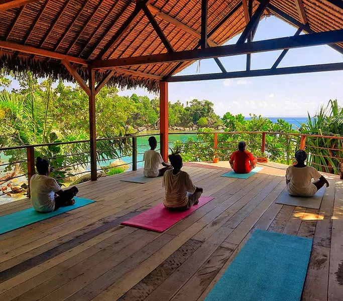 Séance de yoga face à la mer dans un pavillon ouvert au Natiora Green Lodge.